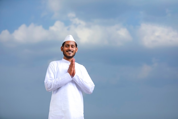 Foto giovane indiano (pellegrino) in abiti tradizionali e dando namaste o gesto di benvenuto.