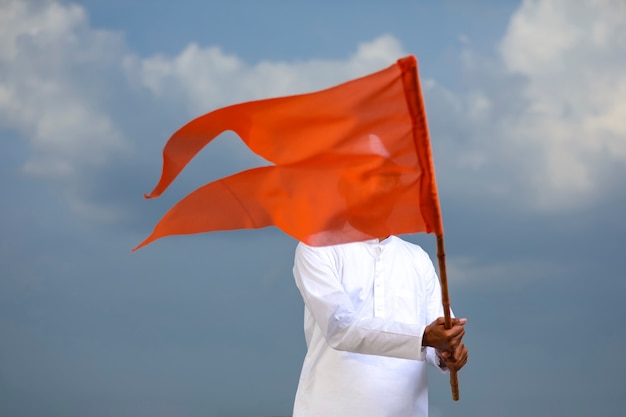 Young indian man (pilgrim) in traditional wear and waving religious flag.