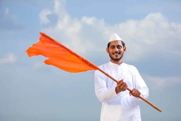 Young indian man (pilgrim) in traditional wear and waving religious flag.