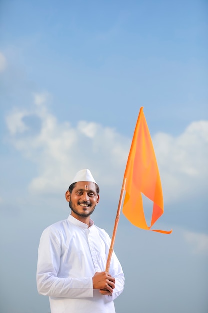 Young indian man (pilgrim) in traditional wear and waving religious flag.