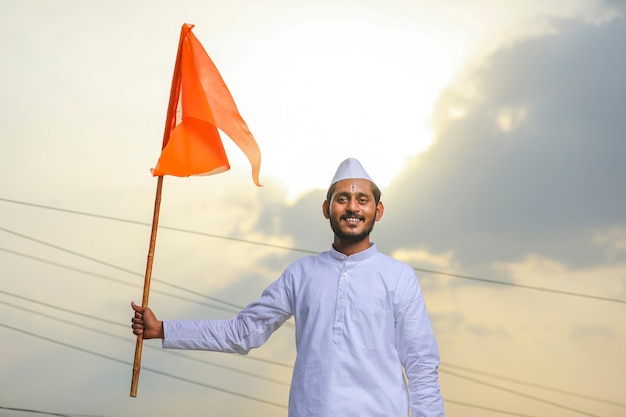 伝統的な服装で宗教的な旗を振っている若いインド人（巡礼者）。