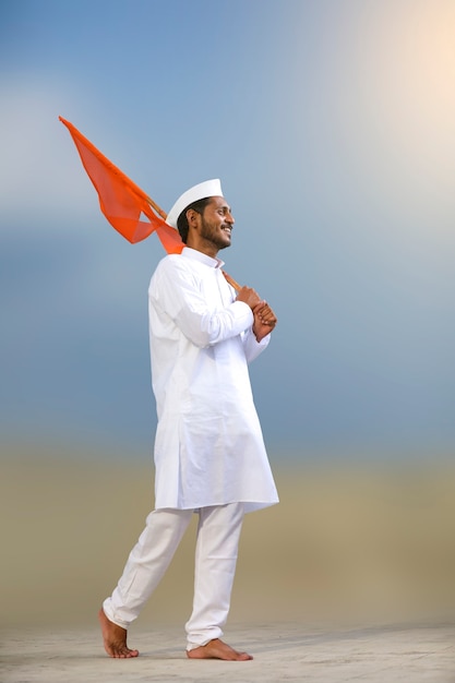 Photo young indian man (pilgrim) in traditional wear and waving religious flag.