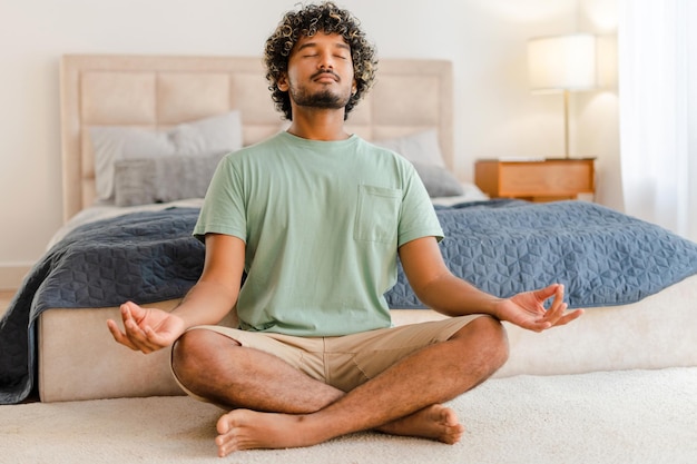 young indian man practicing meditation at home in the morning