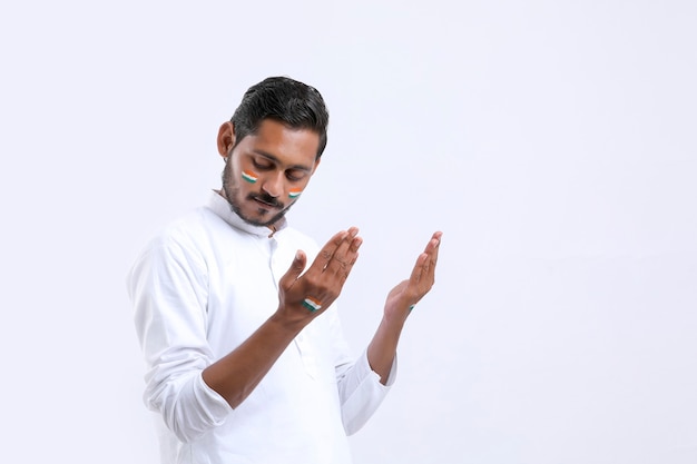 Young indian man praying over white background.