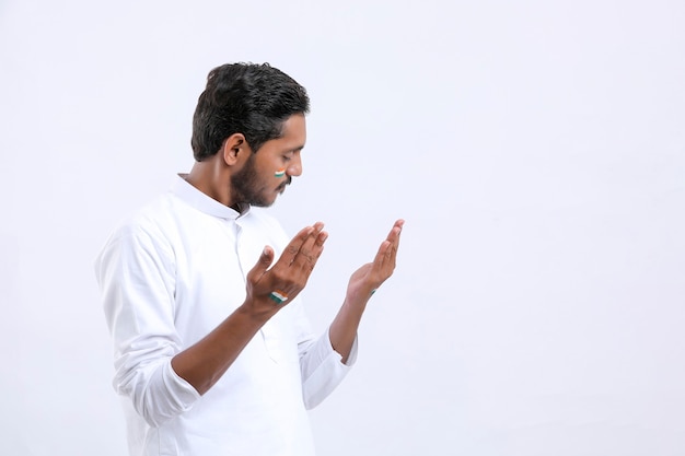 Young indian man praying over white background.