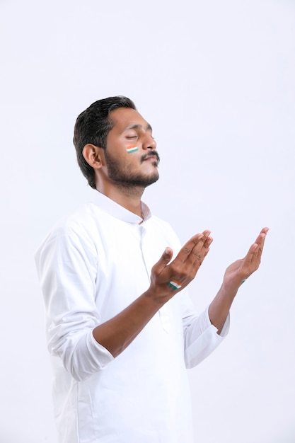 Young indian man praying over white background.