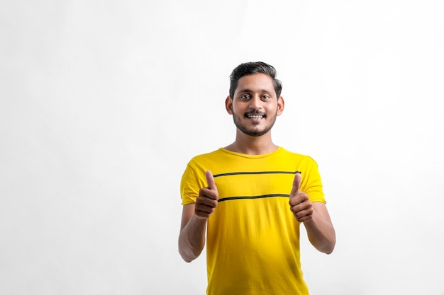 Young indian man showing direction with hand over white background.