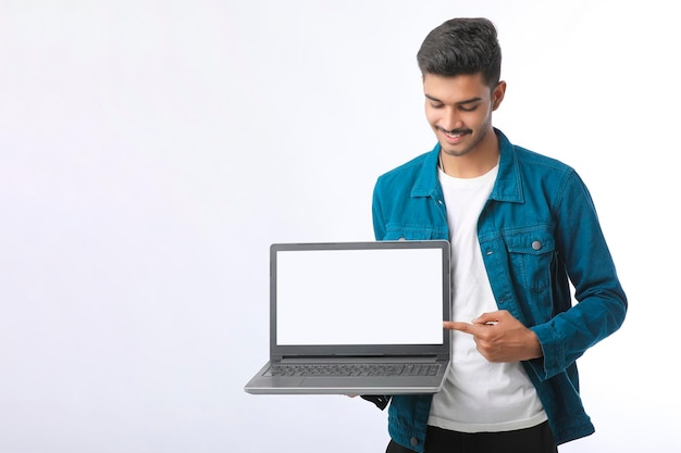 Young indian man showing laptop screen on white background.