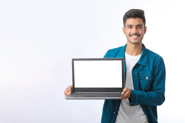 Young indian man showing laptop screen on white background.