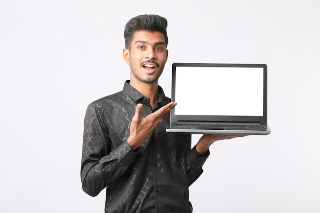 Young indian man showing laptop screen on white background.