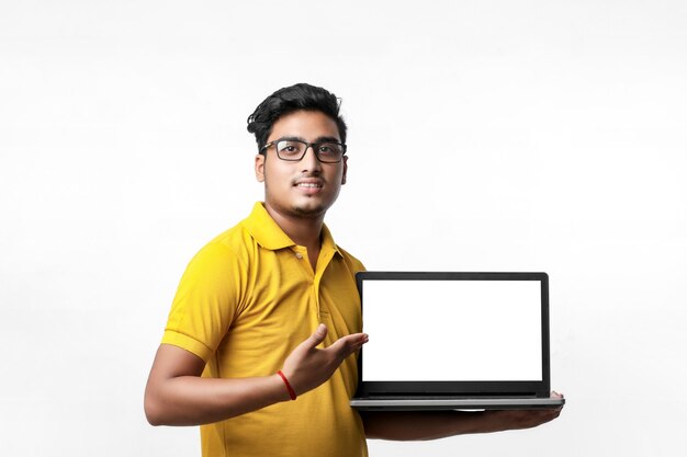 Young indian man showing laptop screen over white background.