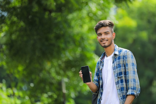 Giovane uomo indiano che mostra lo schermo mobile