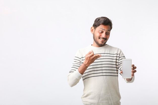 Young indian man showing smartphone screen on white background.