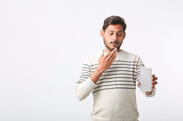 Young indian man showing smartphone screen on white background.