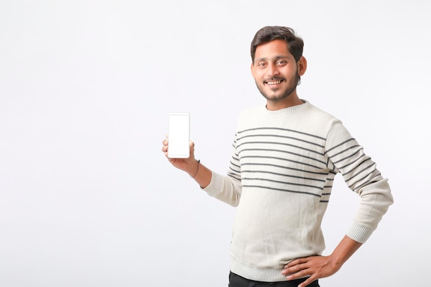 Young indian man showing smartphone screen on white background.