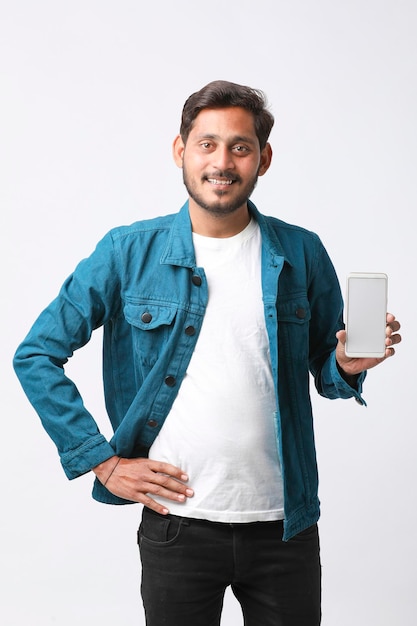 Young indian man showing smartphone screen on white background.