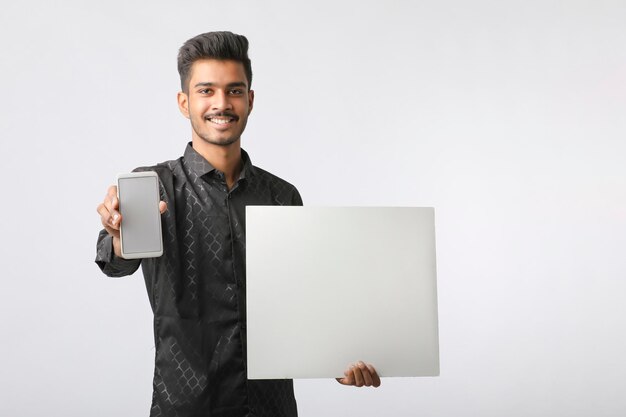 Young indian man showing smartphone screen on white background.