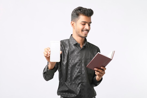 Young indian man showing smartphone screen on white background.