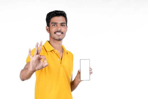 Young indian man showing smartphone on white background.