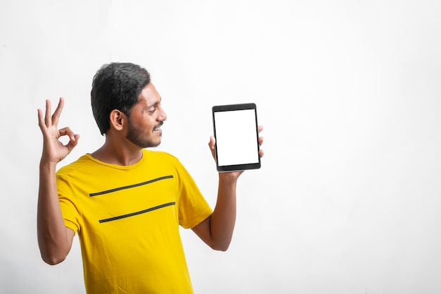 Young indian man showing tablet over white background.