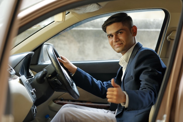 young indian man showing thumps up from car window