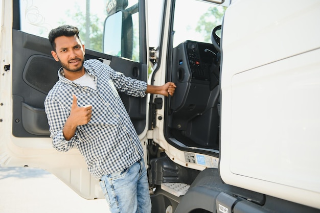 Photo young indian man standing by his truck the concept of freight transportation