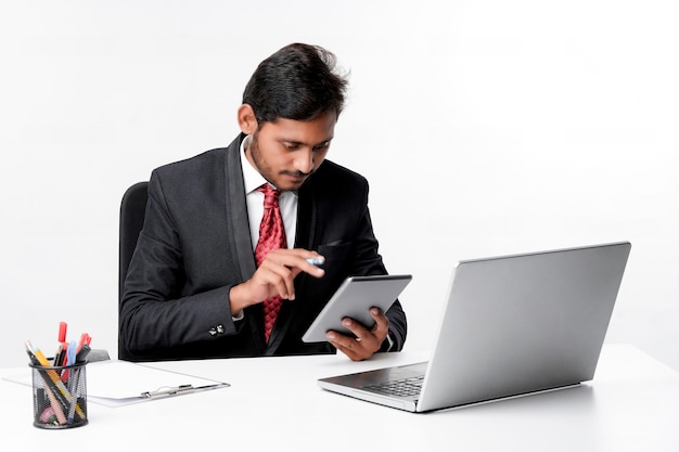 Young indian man in suit and using tablet and laptop at office