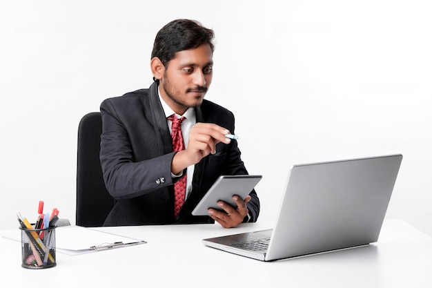 양복을 입고 사무실에서 태블릿과 노트북을 사용하는 젊은 인도 남자