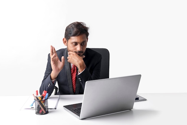 Young indian man in suit and working on laptop at office