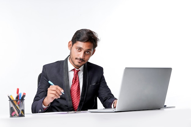 Young indian man in suit and working on laptop and writing some note at office.