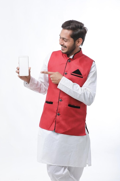 Young indian man in tradition wear and showing smartphone screen on white background.