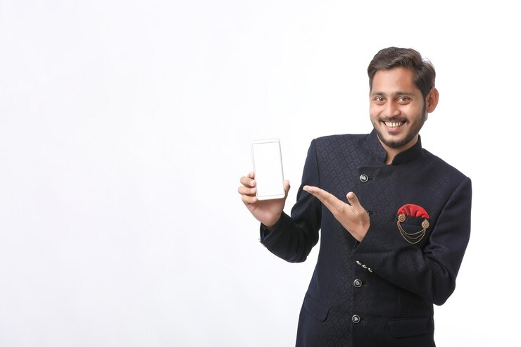 Photo 伝統的な若いインド人は、白い背景にスマートフォンの画面を着用して表示しています。