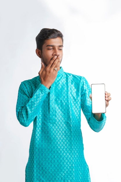 Young indian man in tradition wear and showing smartphone screen on white background.