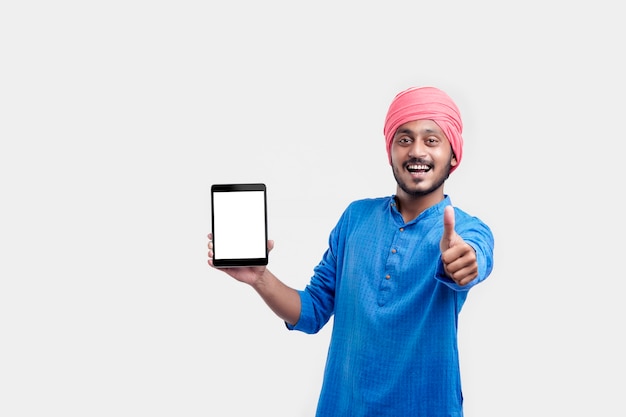 Young indian man in traditional wear and showing tablet over white background.