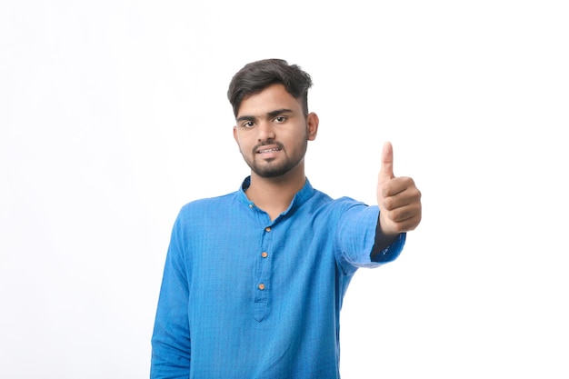 young indian man in traditional wear and showing thumps up on white background.