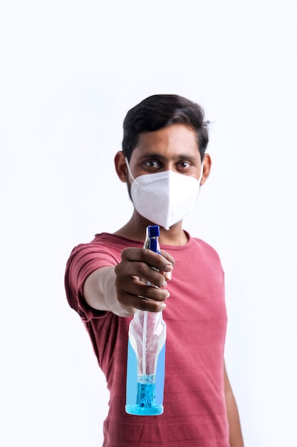 Молодой индийский мужчина использует дезинфицирующее средство для рук для защиты от вируса короны.
