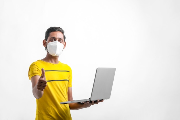 Young indian man using laptop over white background.