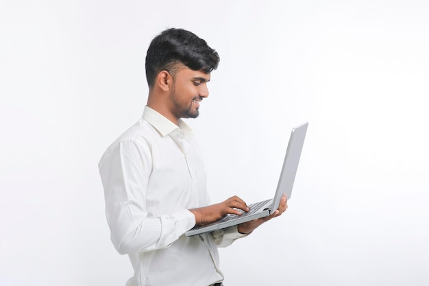 Young indian man using laptop over white background.