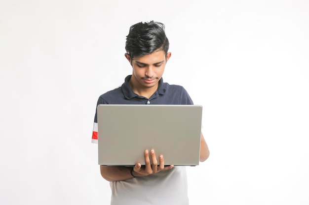 Young indian man using laptop over white background.