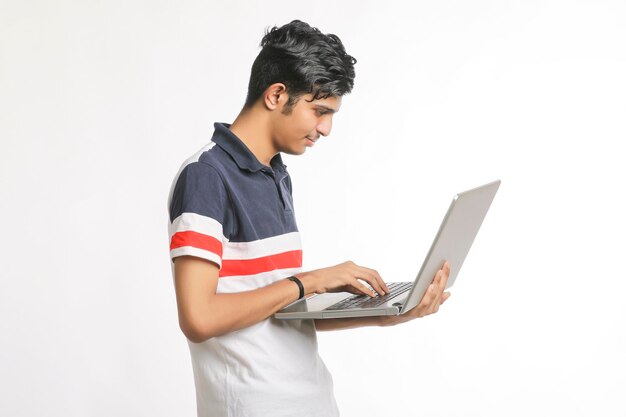 Young indian man using laptop over white background.