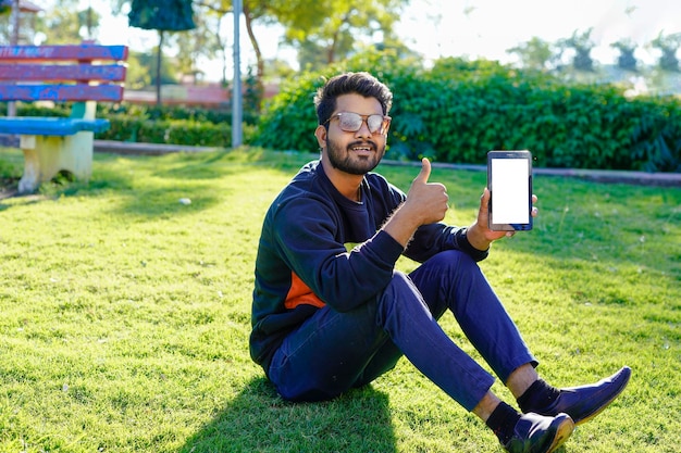 公園でスマートフォンを使用して若いインド人