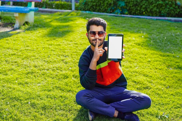 Young indian man using smart phone in park