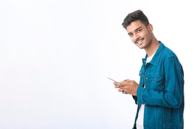 Young indian man using smartphone and giving expression on white background.