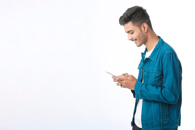 Young indian man using smartphone and giving expression on white background.