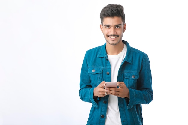 Young indian man using smartphone and giving expression on white background.