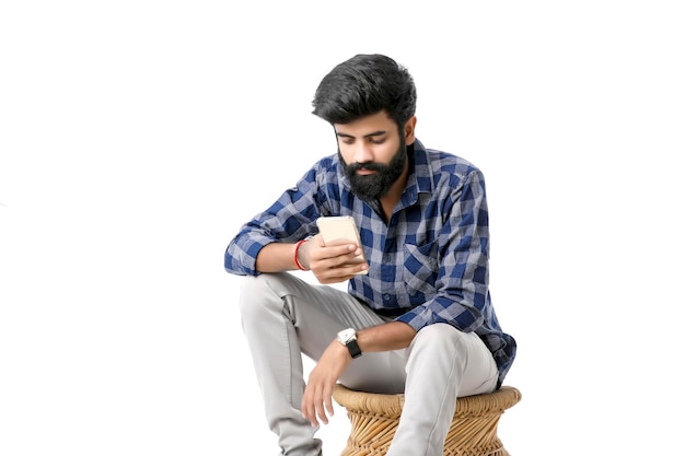 Young indian man using smartphone and giving expression on white background