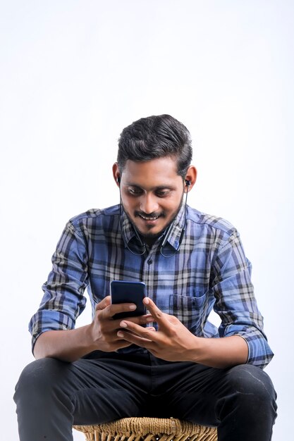 Young indian man using smartphone over white background.