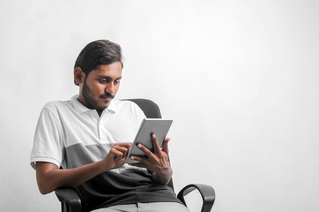 Young indian man using tablet over white background.