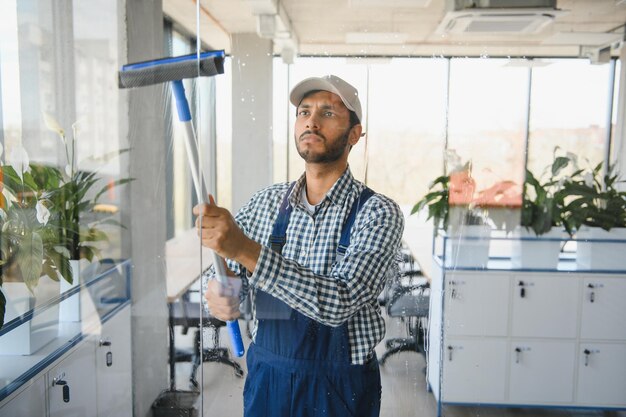 Foto finestra di lavaggio del giovane uomo indiano in ufficio