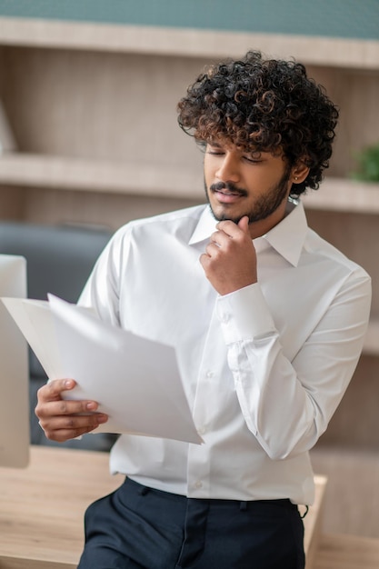 Photo young indian man in a white shirt in the office